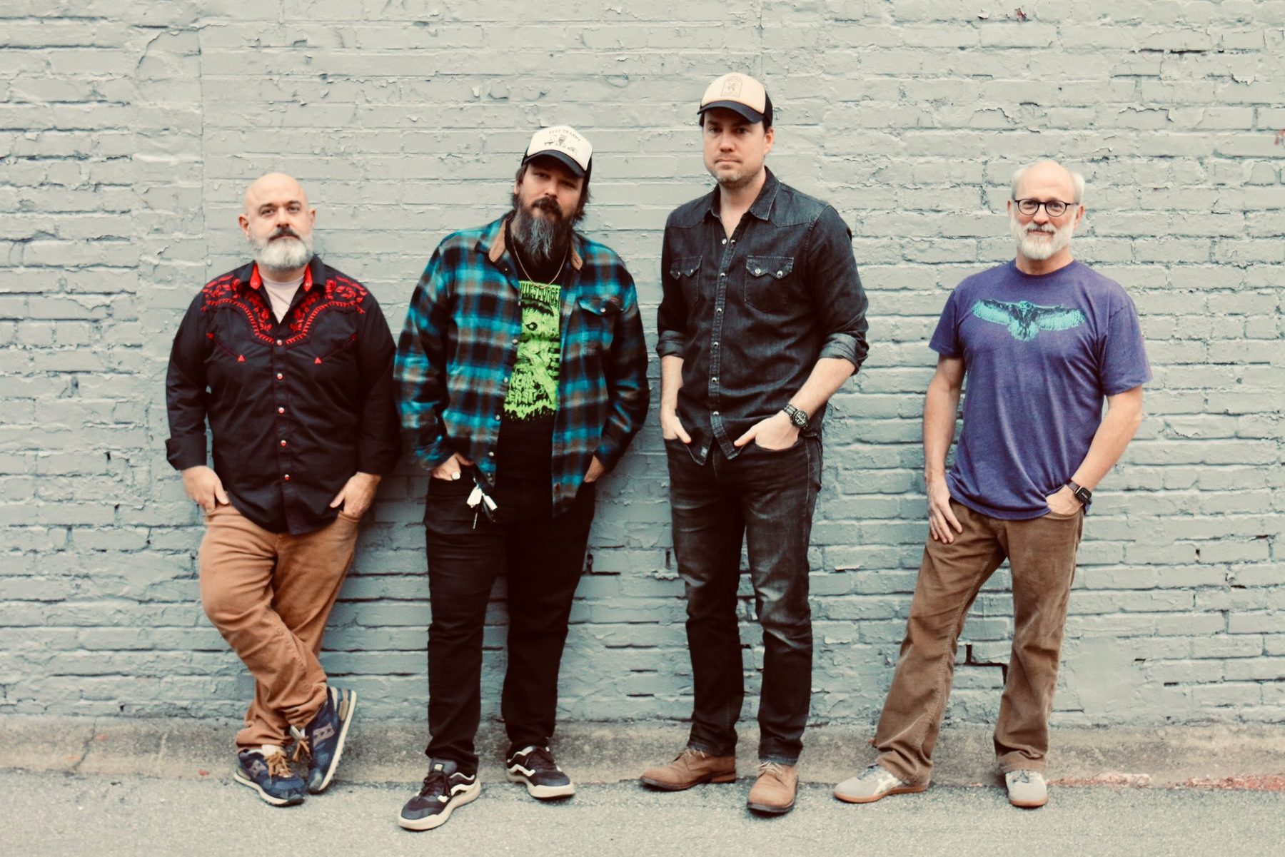The Hainted Blue, four members standing against a painted brick wall
